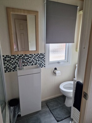 Ein kleines Badezimmer mit Toilette, Waschbecken und Spiegel.