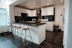 Una cocina moderna con una isla central, taburetes de bar y piso de baldosas negras.