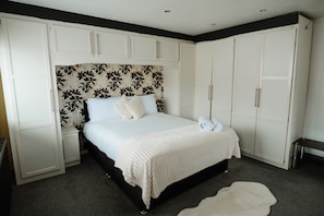 Un dormitorio con cama, armario blanco y cabecera floral.