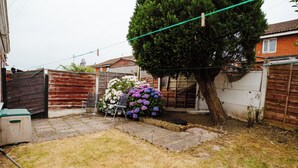 Ein Garten mit Holzzaun, Baum und Metallstuhl.