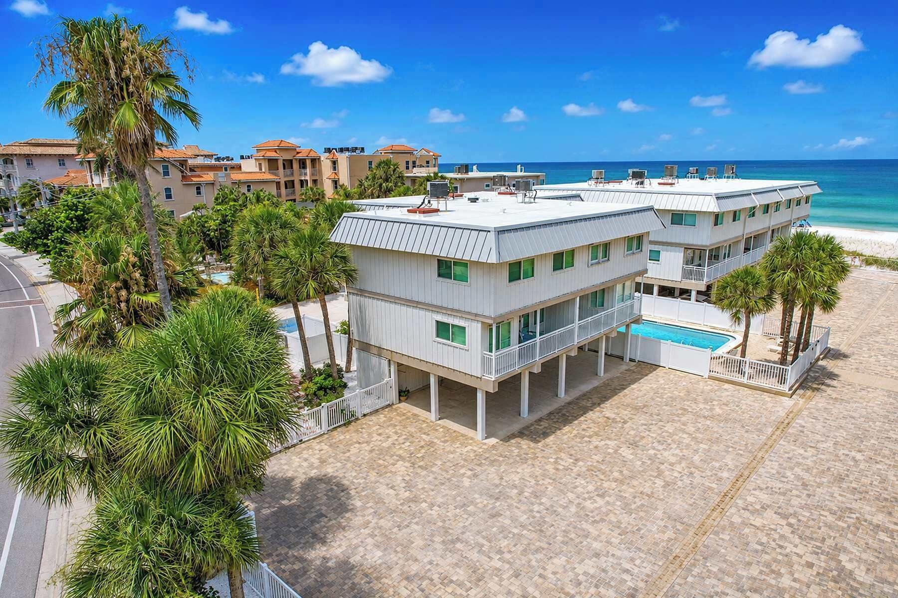 A beachfront hotel with a pool, multiple balconies, and palm trees.