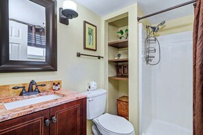 Une salle de bain avec un lavabo en marbre, des toilettes, une douche avec une porte en verre et un miroir.