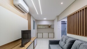 A modern living room with a flat-screen TV, a grey sofa, and a wooden panel wall. - Fully Equipped apt in Downtown Floripa - Ejo0305 (Florianópolis)