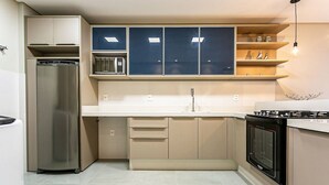 A compact kitchen with a built-in refrigerator, microwave, and oven. - Amazing Studio 5min Walk to the Beach Elu109 (Florianópolis)