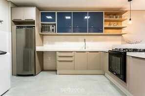 Eine kompakte Küche mit einem integrierten Kühlschrank, einer Mikrowelle und einem Backofen.