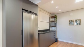 A modern kitchen with a stainless steel refrigerator, a built-in oven, and a wooden countertop. - Fully Equipped apt in Downtown Floripa - Ejo0306 (Florianópolis)