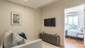 A modern bedroom with a bed, a TV, and a view of the outdoors. - Fully Equipped apt in Downtown Floripa - Ejo0306 (Florianópolis)