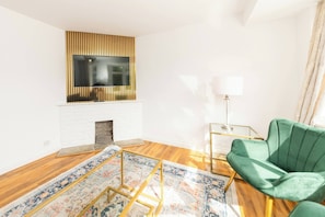 A modern living room with a fireplace, a green sofa, and a patterned rug. - Spacious 5-bedroom House in Berkshire - Perfect Family Retreat (Reading)