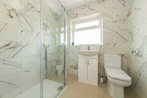 Une salle de bain avec une douche à parois de verre, un lavabo et des toilettes.