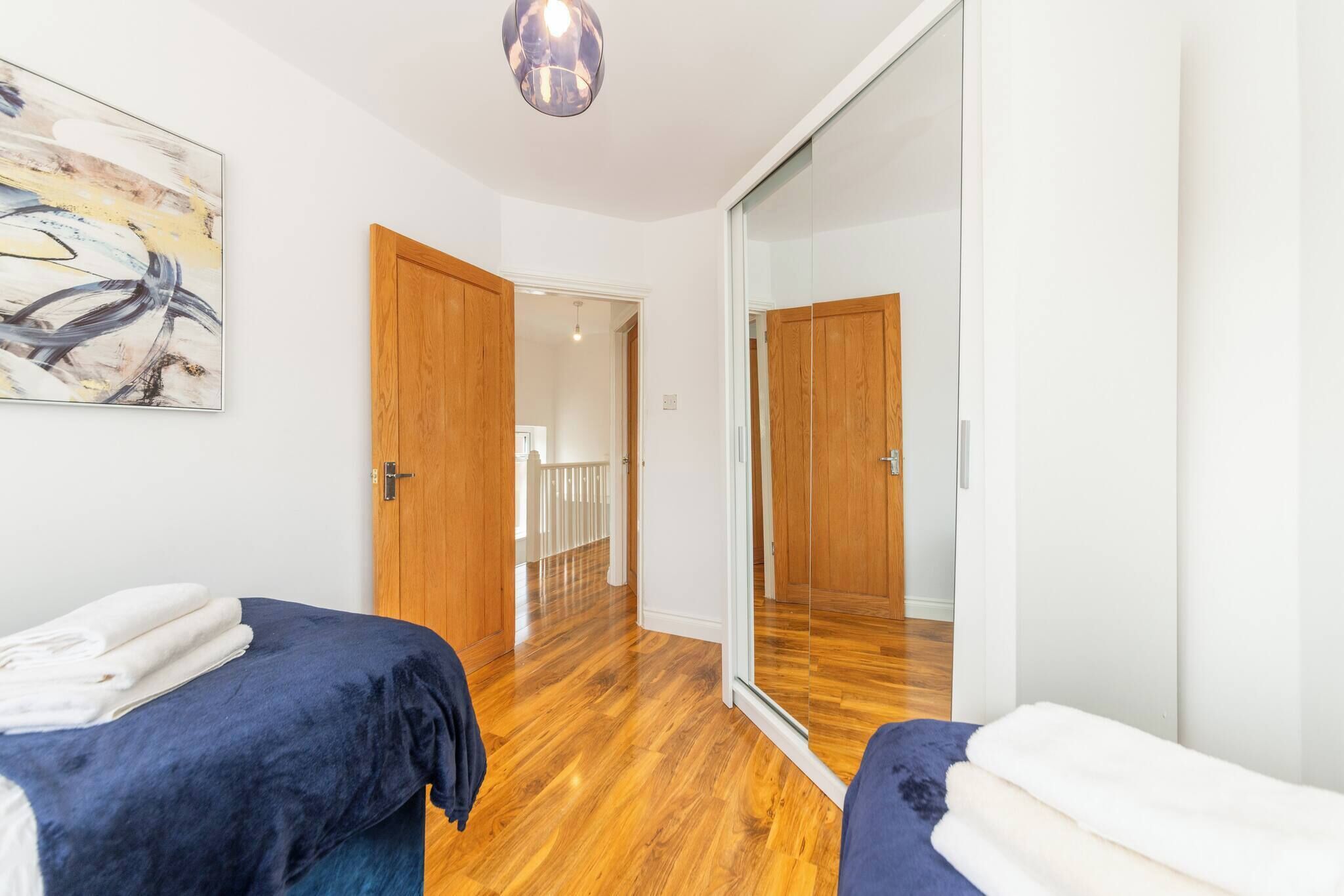 A bedroom with two beds, a large mirror, and a wooden floor.