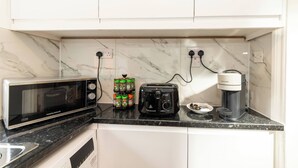 A kitchen with a microwave, toaster, coffee maker, and spice rack. - Spacious 5-bedroom House in Berkshire - Perfect Family Retreat (Reading)