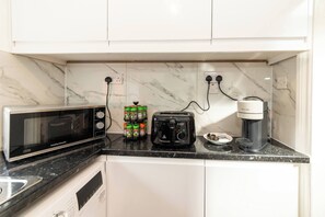 A kitchen with a microwave, toaster, coffee maker, and spice rack. - Spacious 5-bedroom House in Berkshire - Perfect Family Retreat (Reading)