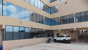 A multi-story building with large windows and a paved courtyard. - SJS Residency by Orange Hotels (Tiruvannamalai)