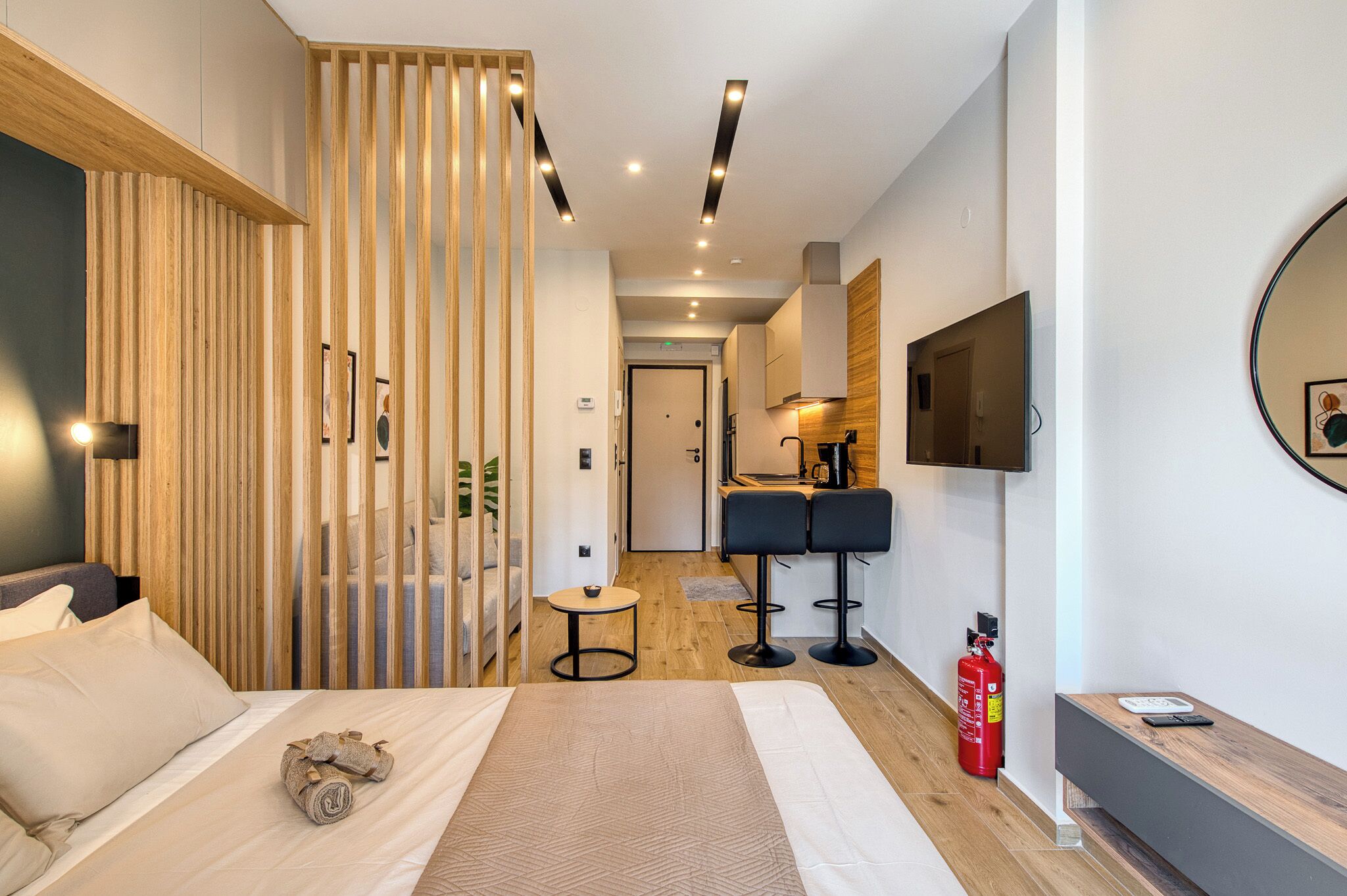 Une chambre d’hôtel moderne équipée d’un lit, d’un bureau, d’une chaise, d’une télévision et d’un extincteur.