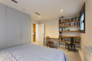 A bedroom with a bed, a desk, two chairs, a bookshelf, and a wardrobe. - Atic Deluxe, excellent location (Barcelona)