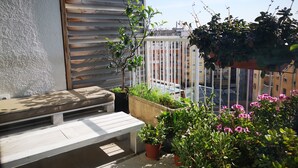 A balcony with a wooden bench, potted plants, and a view of a cityscape. - Atic Deluxe, excellent location (Barcelona)