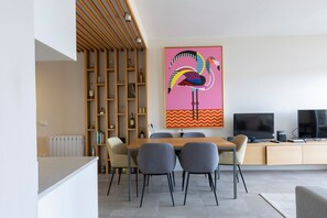 A modern living room with a dining area, a large colorful artwork, and a flat-screen TV. - Atic Deluxe, excellent location (Barcelona)