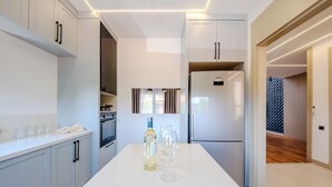 Uma cozinha moderna com forno embutido, geladeira Samsung e bancada de mármore.