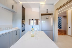A modern kitchen with a built-in oven, a Samsung refrigerator, and a marble countertop.