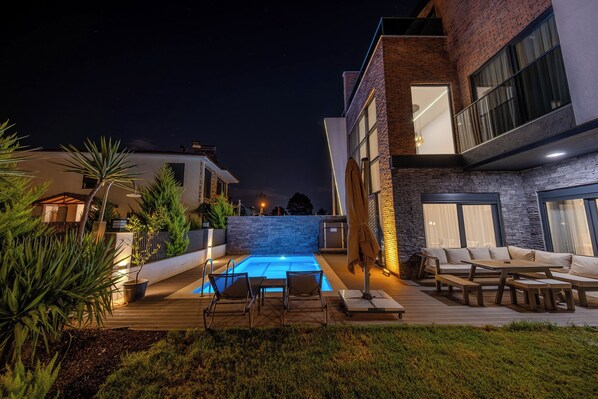 A modern outdoor pool area with lounge chairs and a stone wall.