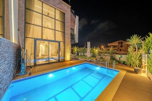 A swimming pool with a glass enclosure, a brick building with large windows, and outdoor seating. - Luxury Forest Villas with Private Pool in ANTALYA (Antalya)