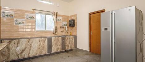 A kitchen with a marble countertop, a refrigerator, and a wooden door.