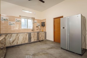 Una cocina con encimera de mármol, un refrigerador y una puerta de madera.