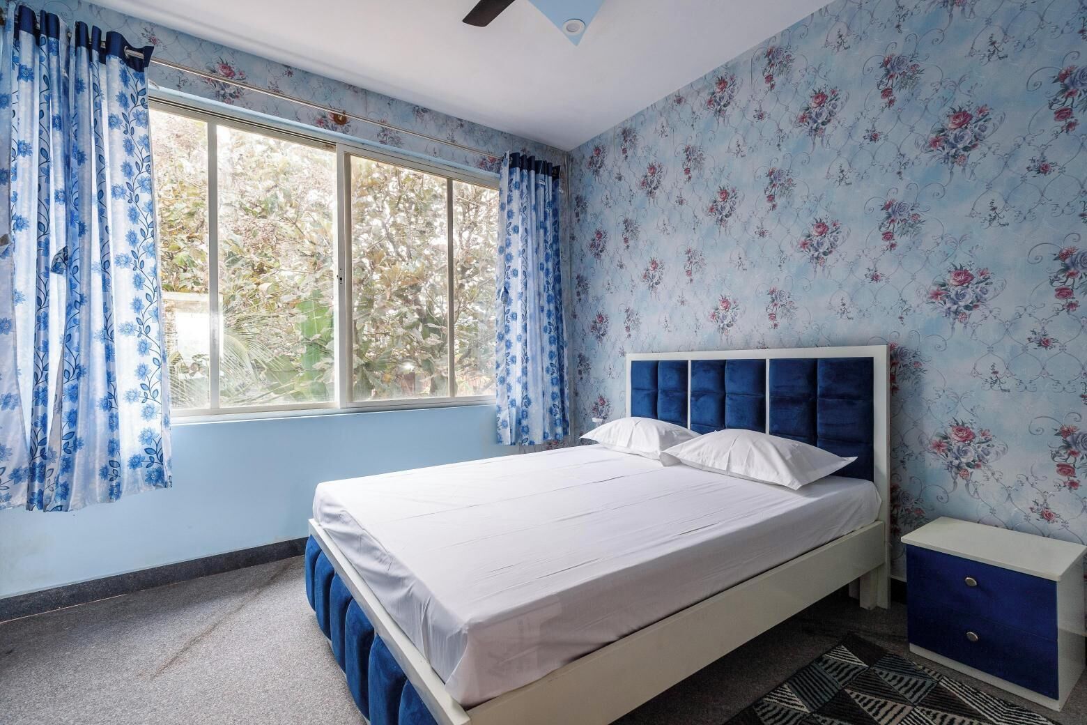 Ein Schlafzimmer mit einem Bett, einem Nachttisch und einem Fenster mit Vorhängen.