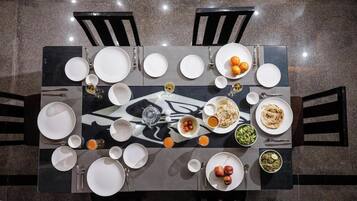 A dining table set with plates, bowls, and glasses, surrounded by chairs.