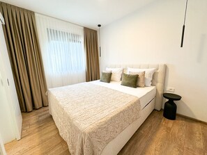 Ein Hotelzimmer mit einem großen Bett, einem Nachttisch und einem Vorhangfenster.