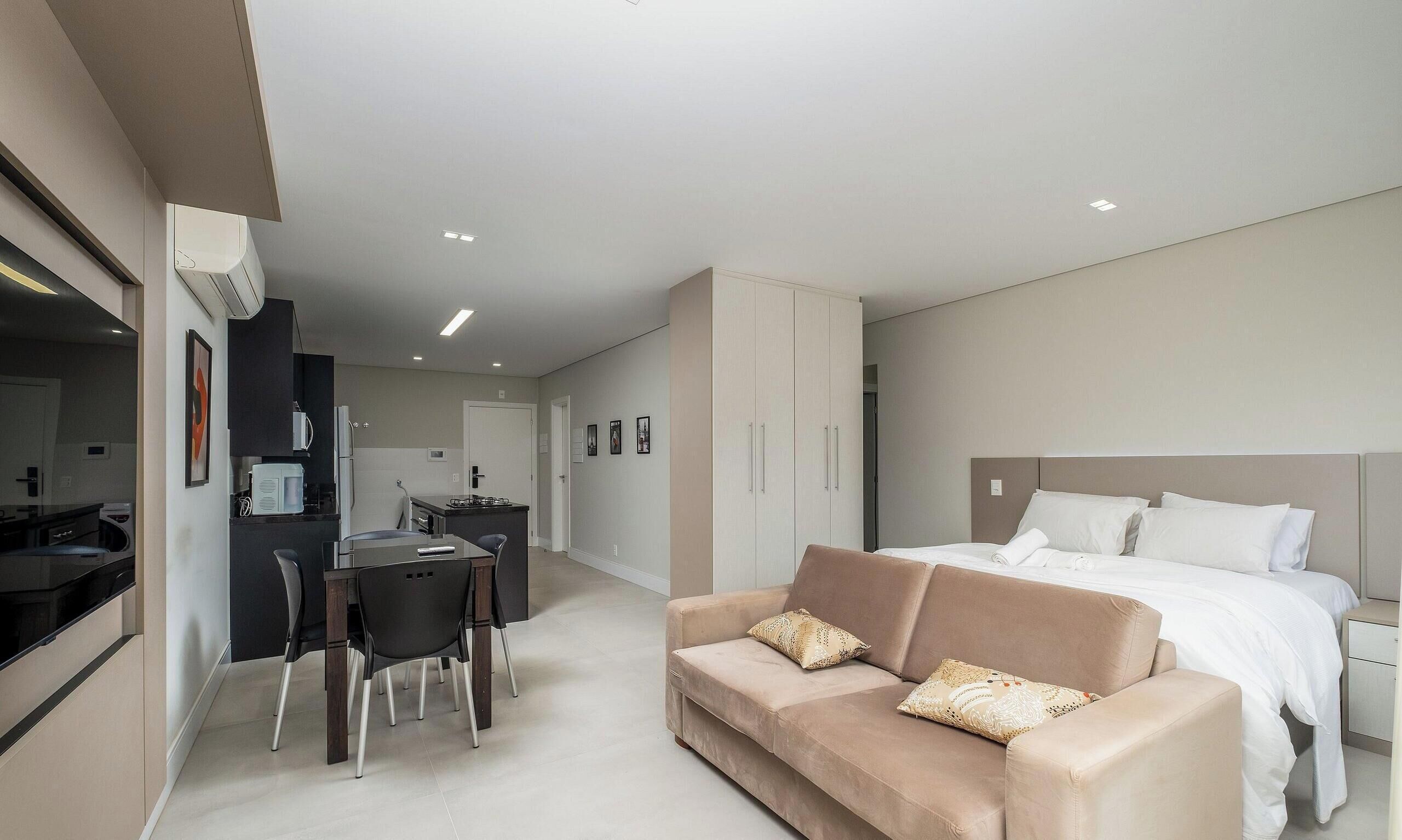 Una habitación de hotel moderna con cama, sofá, zona de comedor y kitchenette.