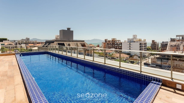 A rooftop swimming pool with a clear view of the cityscape and mountains in the background. - Modern Studio 4 Minutes From Jurere Beach Elu207 (Florianópolis)