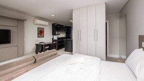 A modern hotel room with a large bed, a sofa, a desk, and a kitchenette. - Modern Studio 4 Minutes From Jurere Beach Elu207 (Florianópolis)