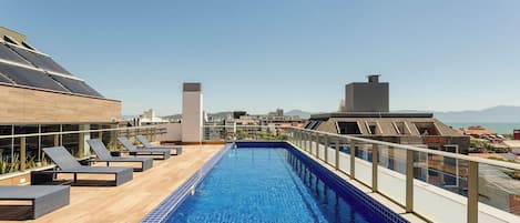 Ein Pool auf dem Dach mit Liegestühlen und Blick auf die Stadtlandschaft.
