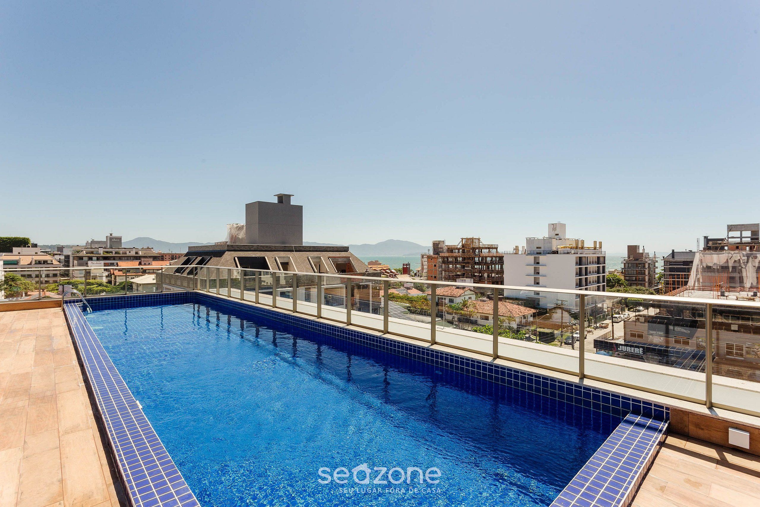 Una piscina sul tetto con vista panoramica sulla città e montagne sullo sfondo.