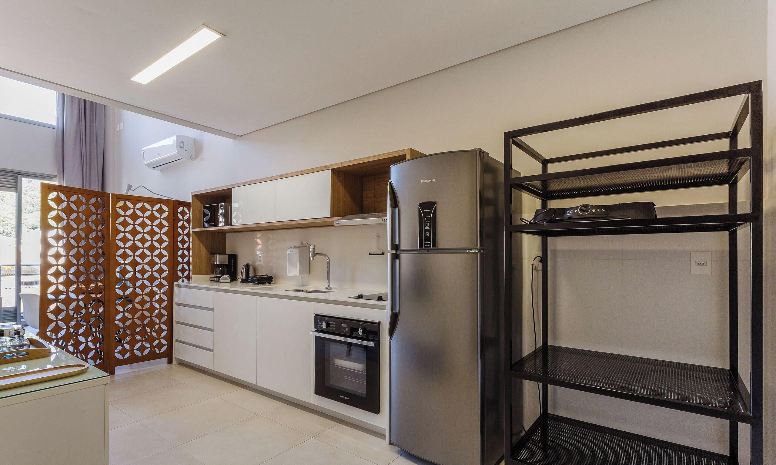 Una cocina moderna con horno integrado, refrigerador y una estantería metálica negra.
