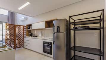 Una cocina moderna con horno integrado, refrigerador y una estantería metálica negra.
