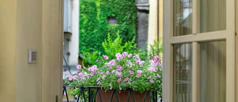 A potted plant with pink flowers in a metal stand on a balcony.