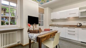 Une cuisine moderne avec des meubles blancs, une table en bois et une chaise.