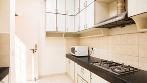 A kitchen with white cabinets, a black countertop, a stove, and a microwave.