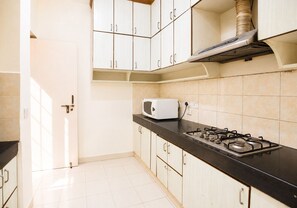 A kitchen with white cabinets, a black countertop, a stove, and a microwave.