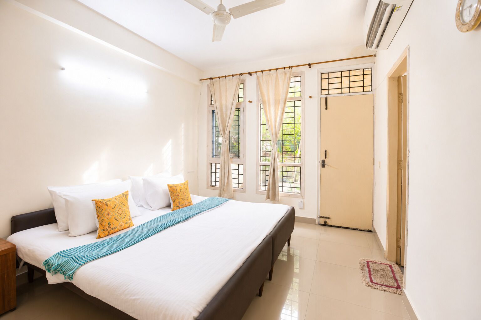Habitación de hotel con cama, cortinas, ventilador de techo y una puerta.