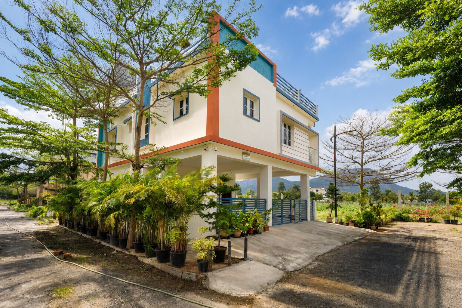A two-story building with a balcony, surrounded by lush greenery and potted plants.