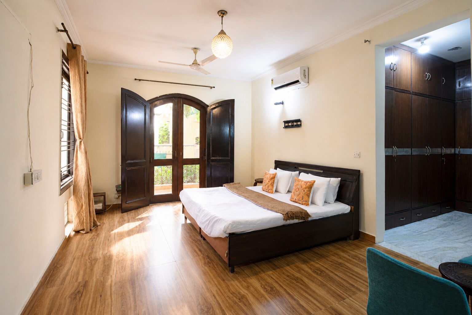 A hotel room with a bed, a ceiling fan, an air conditioning unit, and a wardrobe.