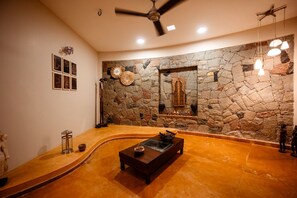 Un cuarto de spa con pared de piedra, un banco de madera y un ventilador de techo.