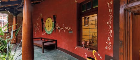 Una habitación con un banco de madera, una pared decorativa con diseños pintados y una ventana con vistas.