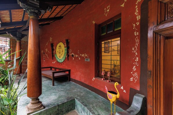 A room with a wooden bench, a decorative wall with painted patterns, and a window with a view.