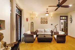 A living room with a sofa set, a coffee table, a ceiling fan, wall-mounted lights, and a clock.