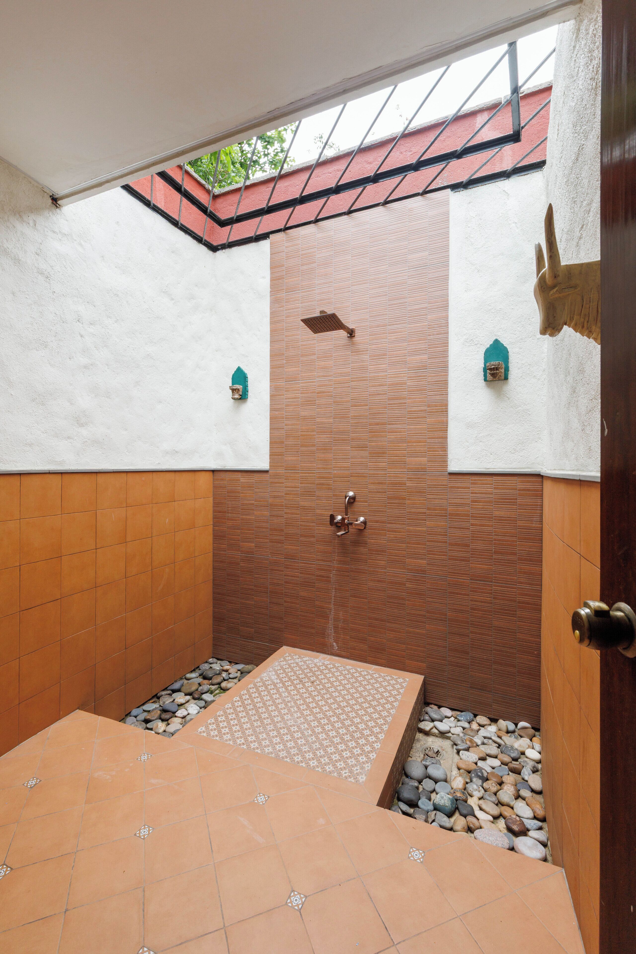 A bathroom with a tiled floor, a shower area, and a decorative wall.