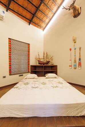 Un dormitorio con una cama grande, un modelo de barco, una cabeza de ciervo y una pared con tres adornos.